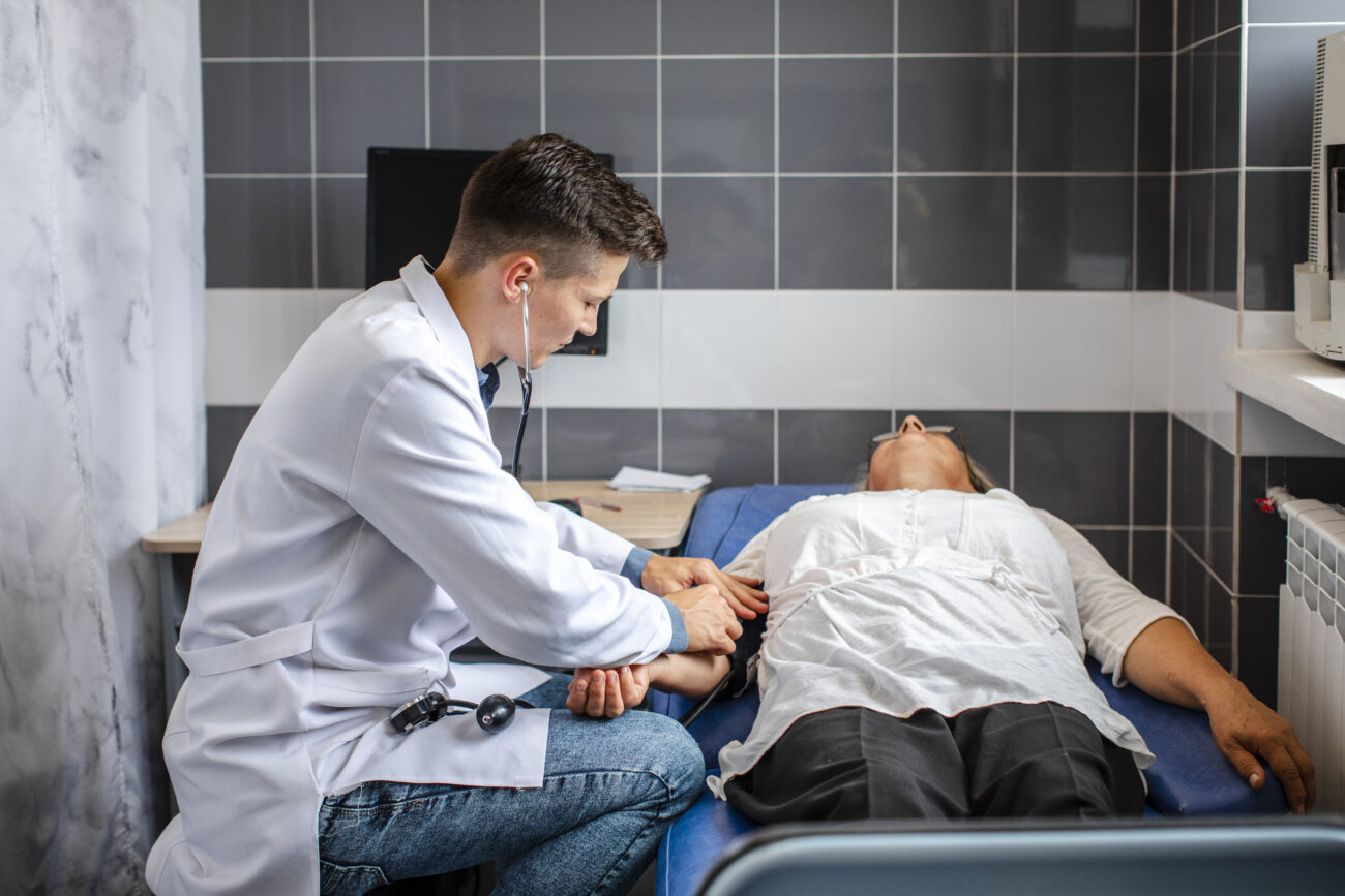 A General Practitioner attending to a patient in an emergency clinic, symbolising urgent care preparedness after online emergency medicine training.